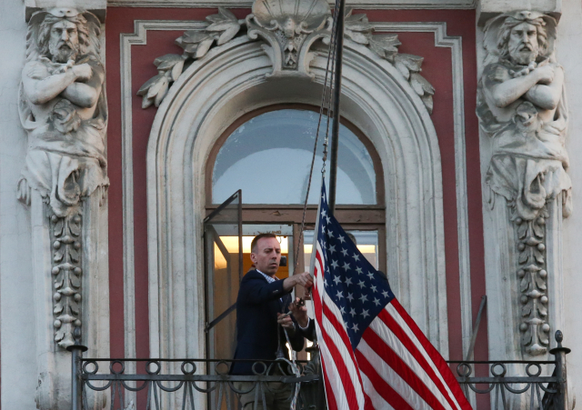 Muž odstraňuje vlajku z ambasády USA v Petrohradě. 