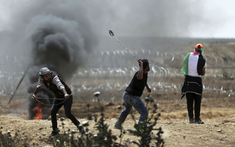 Palestinští protestující házející kameny na izraelské vojáky. Palestinští protestující házející kameny na izraelské vojáky.