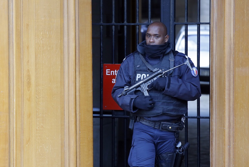 Policista hlídá vchod do budovy.