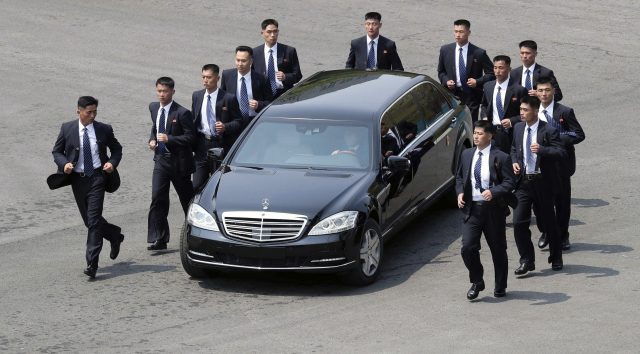 Kim Čong-un v limuzíně a jeho ochranka. 