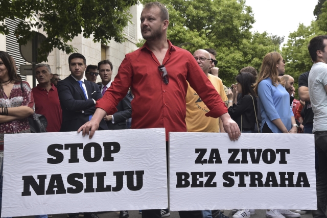 Protest v černohorské Podgorice, muž drží transparenty s nápisy "Stop násilí" a "Za život bez strachu".