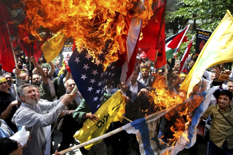 Demonstranti pálící vlajku USA a Izraele při protestech v Gaze.
