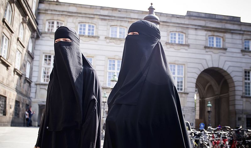 Ženy zahalené v nikábu procházejí před budovou dánského parlamentu v Kodani (ilustrační foto).