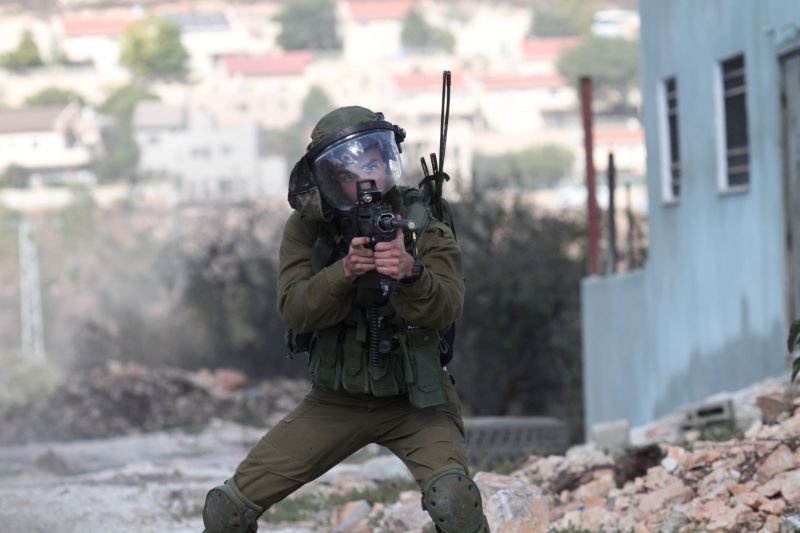Izraelský voják míří na protestující Palestince.