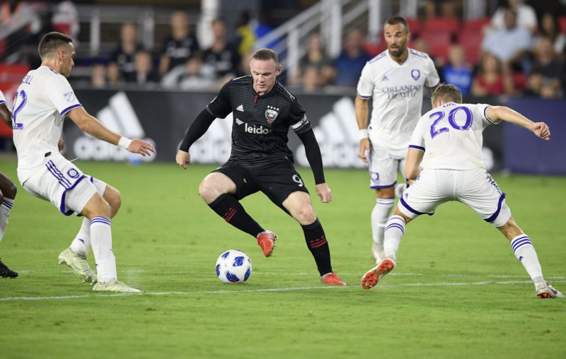 Wayne Rooney (v černém) v obležení obránců soupeře. 