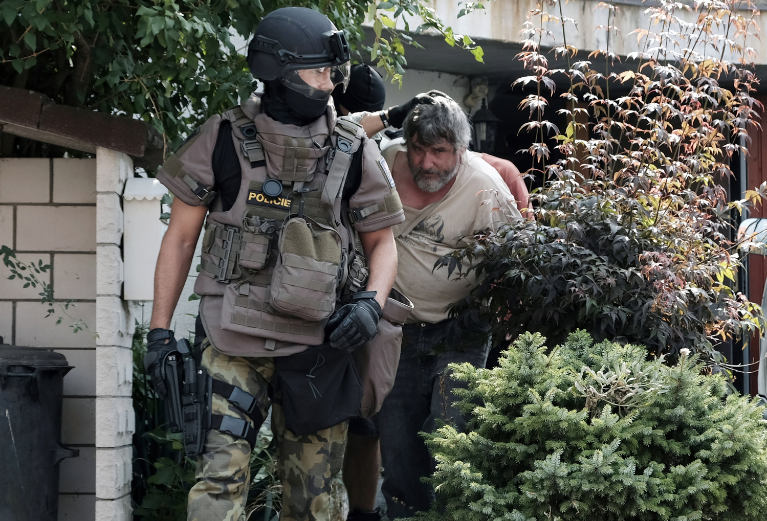 Policisté odvádí zadrženého muže. Policisté odvádí zadrženého muže.
