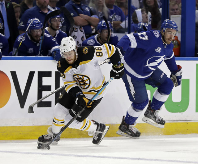 Vlevo David pastrňák v dresu Boston Bruins.