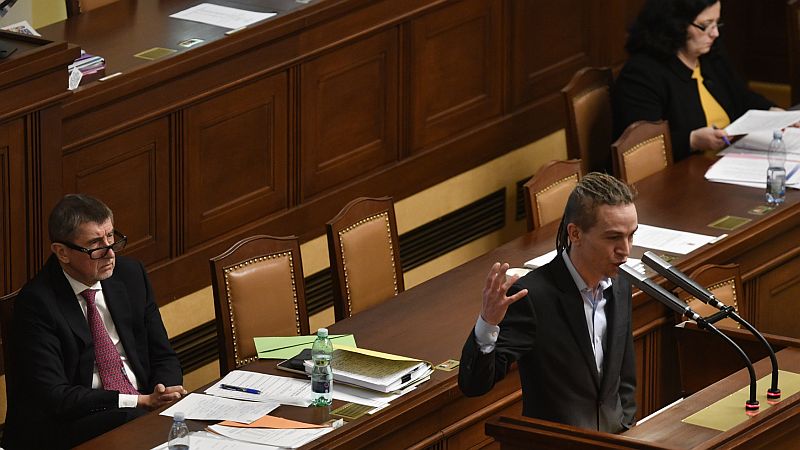 Předseda Pirátů Ivan Bartoš u řečnického pultíku, v pozadí premiér a předseda hnutí ANO Andrej Babiš.