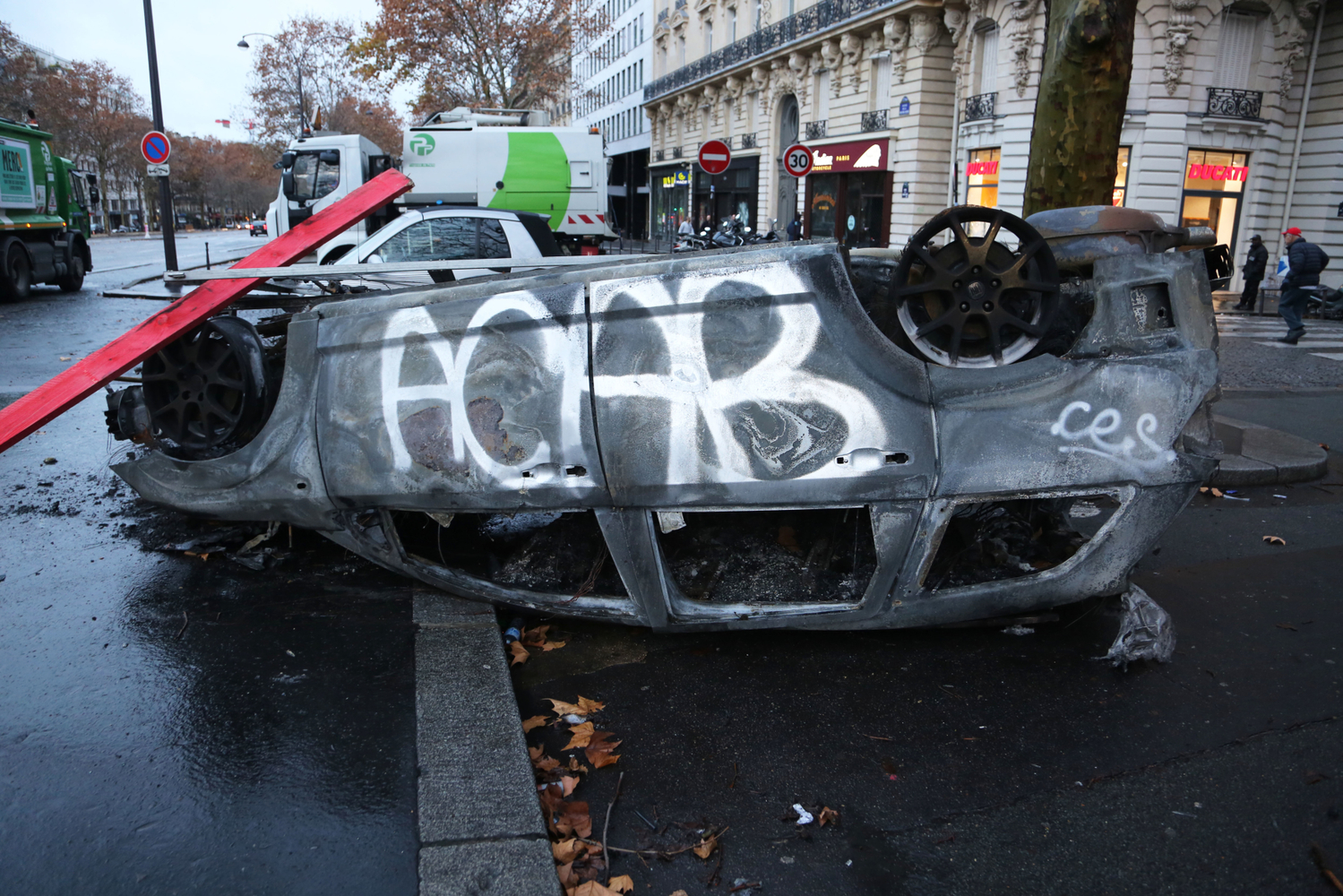 Posprejované ohořelé auto - následky demonstrací v Paříži. Posprejované ohořelé auto - následky demonstrací v Paříži.