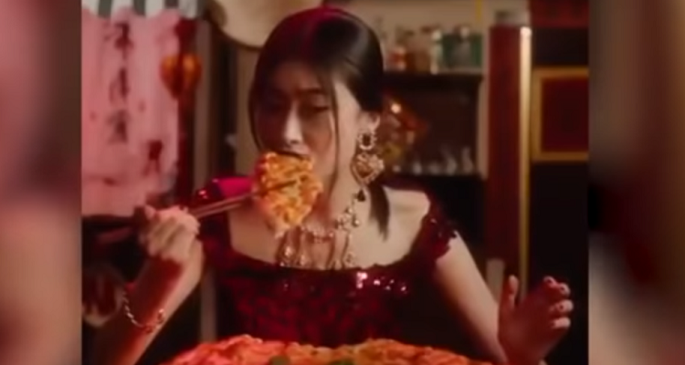Asiatka konzumuje pizzu hůlkami. 