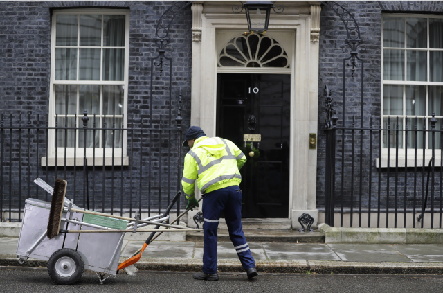 Pracovník uklízí před Downing Street. 
