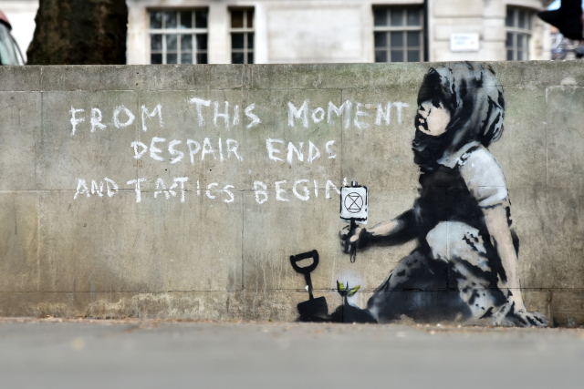 Dívenka na graffiti klečí u právě zasazené květiny a drží v ruce logo skupiny Extinction Rebellion (Rebelie proti vyhynutí), která londýnské protesty za ochranu klimatu organizovala.