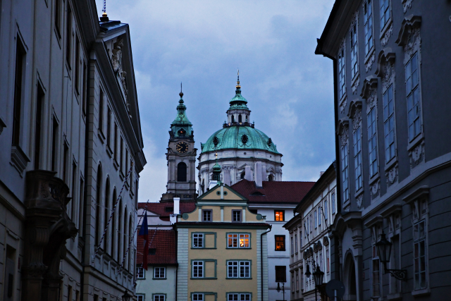 Večerní pohled ze Sněmovní ulice na věže kostela sv. Mikuláše v Praze na Malé Straně.