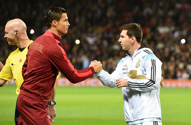 Cristiano Ronaldo (vlevo) se na dálku přetahuje s Lionelem Messim (vpravo).