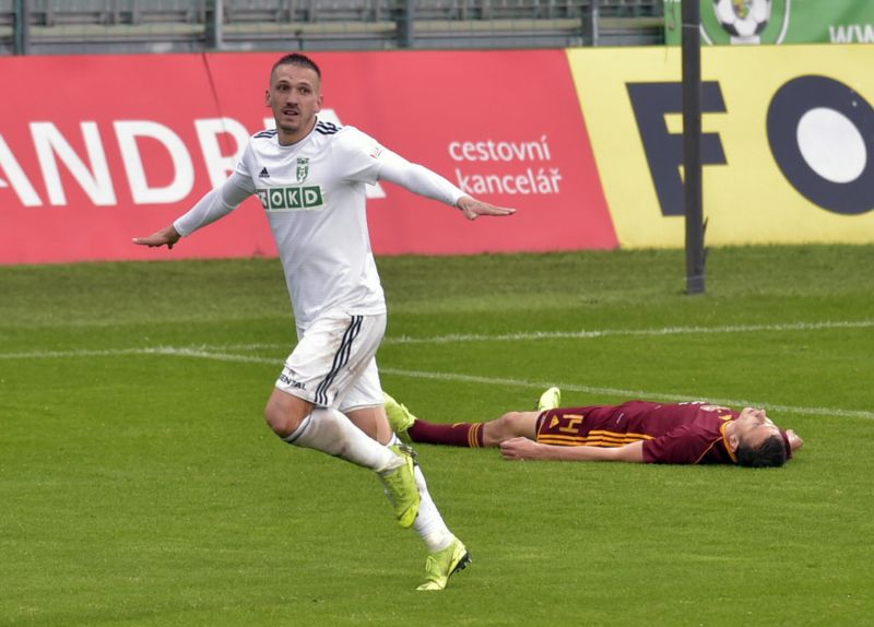 Karvinský David Guba se raduje ze vstřelené branky. Na trávníku leží Ivan Ostojič z Dukly.