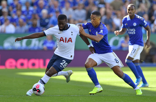 Tanguy Ndombele z Tottenhamu (vlevo) se snaží uchránit míč před hráči Leicesteru.