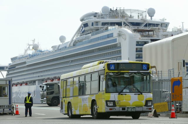 Loď Diamond Princess a autobus určený k evakuaci pasažérů.