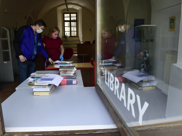 Pracovníci knihovny olomoucké Univerzity Palackého 15. dubna 2020 u výdejního okénka chystají objednané knihy. 