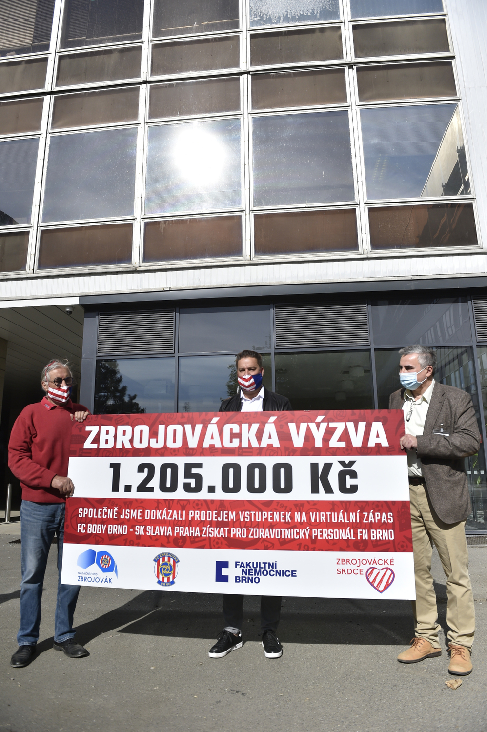 Předseda představenstva fotbalového klubu Zbrojovka Brno Václav Bartoněk (vlevo) a bývalý fotbalista Petr Švancara (uprostřed) předali 7. května 2020 řediteli Fakultní nemocnice Brno Jaroslavu Štěrbovi (vpravo) na boj s pandemií nového koronaviru šek na více než milion korun.
