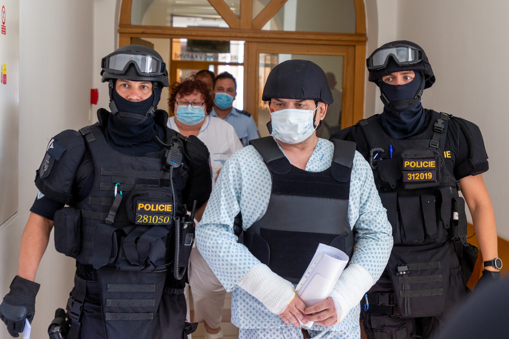 Policisté přivádějí 11. srpna 2020 k jednání u okresního soudu v Karviné muže (uprostřed), kterého policie obvinila z vraždy a obecného ohrožení v souvislosti s požárem panelového domu v Bohumíně. 