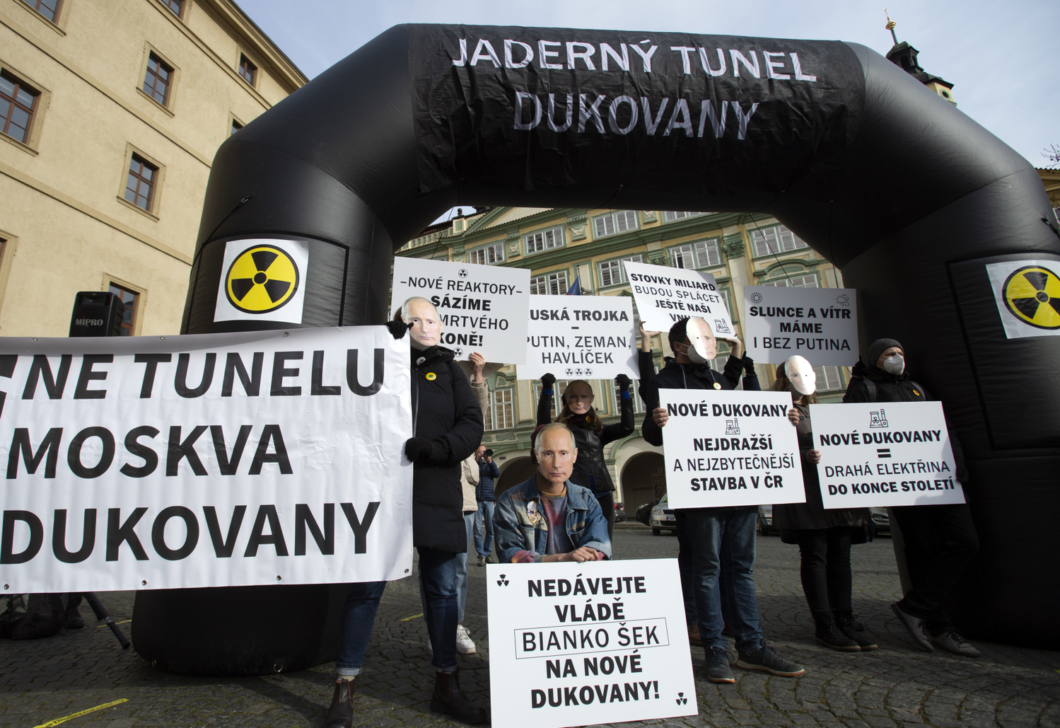 Demonstranti s transparenty a v maskách ruského prezidenta Vladimira Putina.