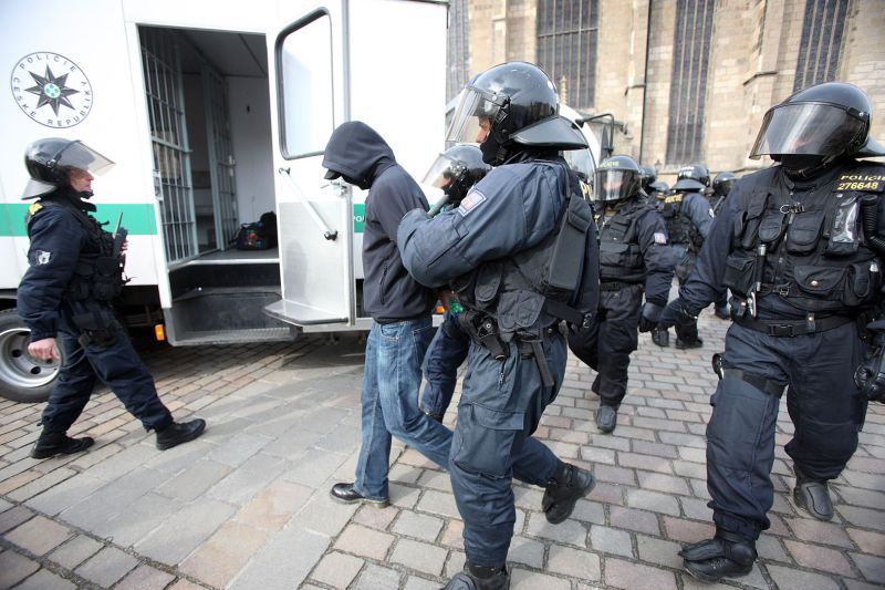 Policisté odvádějí zakuklence.