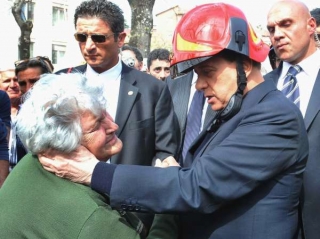 Berlusconi v přilbě hasiče utěšuje ženu v Aquile.