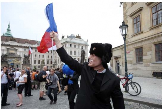 Ruská beranice a červené pole na české vlajce se srpem a kladivem.