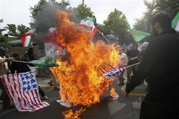 Státními médii poskytnuté foto demonstrantů pálících západní vlajky.