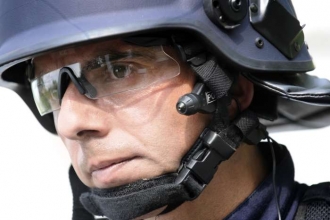 Policista s minikamerou u levého ucha.