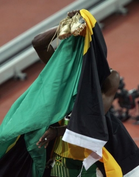 Usain Bolt pod jamajskou vlajkou, mezi hř&iacute;&scaron;n&iacute;ky pr&yacute; nen&iacute;.