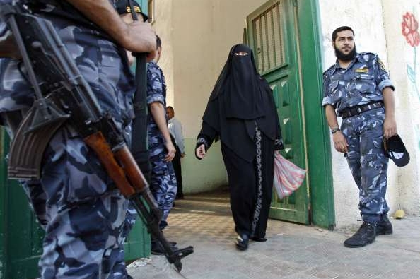 Palestinka jde kolem hlídek Hamasu.