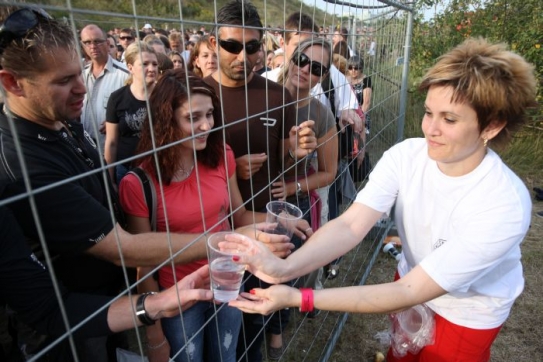 Organizátoři rozdávají vodu k občerstvení.