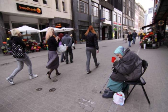 Žebrající důchodkyně před bankou ve Starém městě v Rize.