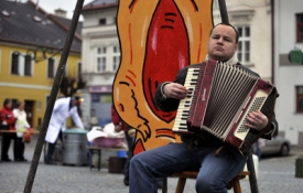 Harmonikář před atrapou ladovsky vyobrazeného zlatého prasete.