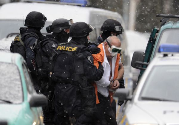 Policisté odvádějí únosce z banky v poutech. 