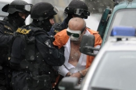 Policisté odvádějí lupiče z banky.