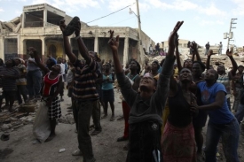 Obyvatelé Haiti chytají humanitární pomoc.