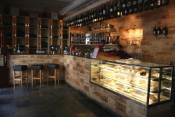 Uvnitř oslní povedený bar s desítkami aranžovaných lahví vína. Uvnitř oslní povedený bar s desítkami aranžovaných lahví vína.