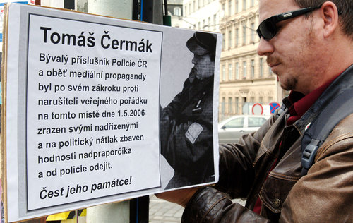 Účstník demonstrace čte plakát o policistovi Tomáši Čermákovi.