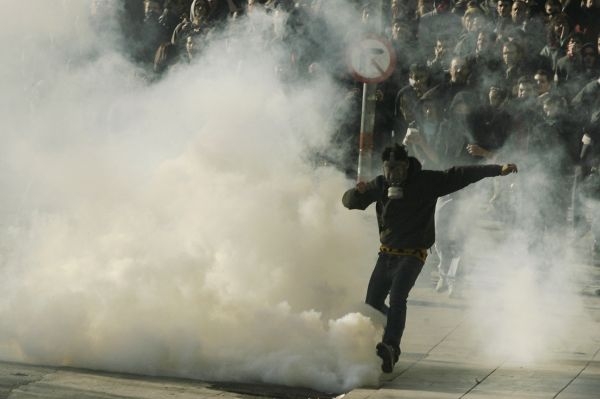 Jeden z demonstrantů odkopává kanystr se slzným plynem.