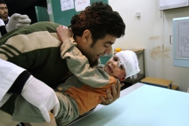 Palestinec přin&aacute;&scaron;&iacute; do nemocnice chlapce zraněn&eacute;ho při bombardov&aacute;n&iacute;.