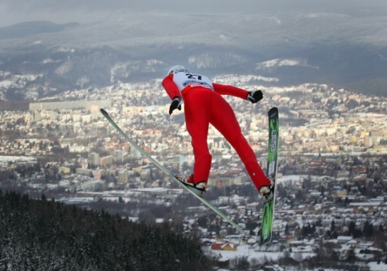 Pohled na skokana na lyžích a město Liberec krátce po odrazu z můstku. Pohled na skokana na lyžích a město Liberec krátce po odrazu z můstku.