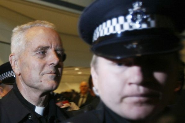 Biskup Williamson přijíždí pod dozorem policie do Británie.