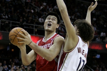 Čínský basketbalista Ho Yao Ming (11)z Houstonských Rockets se pokouší dostat přes Brazilce Andersona Varejao (17) z Cleveland Cavaliers ve druhé čtvrtině NBA v Cleavelandu.