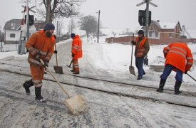 Pracovn&iacute;ci Česk&yacute;ch drah čist&iacute; sněhem zanesen&yacute; železničn&iacute; přejezd.