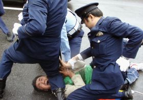 Japonská policie pacifikuje muže, který se snažil narušit štafetu. Japonská policie pacifikuje muže, který se snažil narušit štafetu.