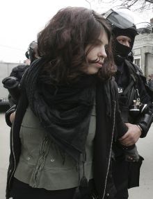 Policie odv&aacute;d&iacute; zadrženou d&iacute;vku protestuj&iacute;c&iacute; proti summitu NATO.
