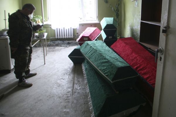 Jihoosetský voják stojí u rakví s těly civilistů.