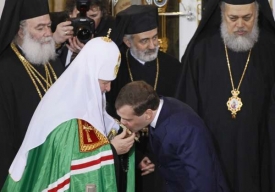 Prezident Medvěděv líbá ruku nového patriarchy.